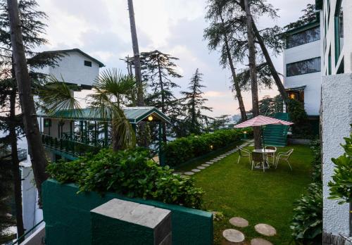 a garden with a table and chairs and a building at Honeymoon Inn Shimla in Shimla