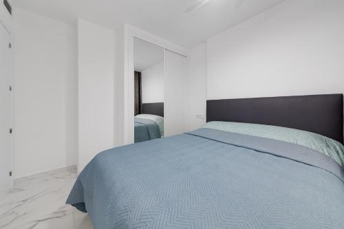 a bedroom with a blue bed in a white room at Modern Apartment Bergantin in Torrevieja