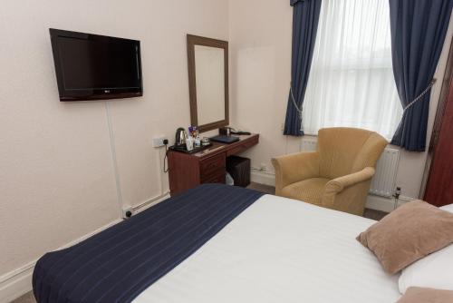 a hotel room with a bed and a mirror and a chair at Devonshire Park Hotel in Eastbourne