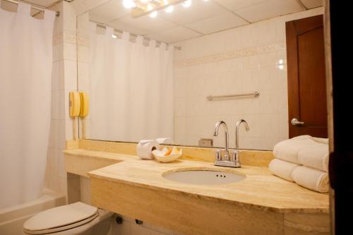 a bathroom with a sink and a toilet and a mirror at Hotel Faranda Express Puerta Del Sol Barranquilla, A Member of Radisson Individuals in Barranquilla