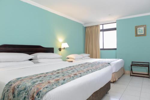 two beds in a hotel room with blue walls at Hotel Faranda Express Puerta Del Sol Barranquilla, A Member of Radisson Individuals in Barranquilla