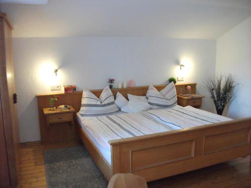 ein Schlafzimmer mit einem großen Bett mit weißer Bettwäsche und Kissen in der Unterkunft Schneiderhof Ferienwohnung mit Alpenblick in Fischbachau