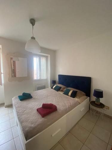 - une chambre avec un grand lit et 2 serviettes rouges dans l'établissement Joli Appart 29m2 en Vieille Ville Menton 2 mins de la mer, à Menton