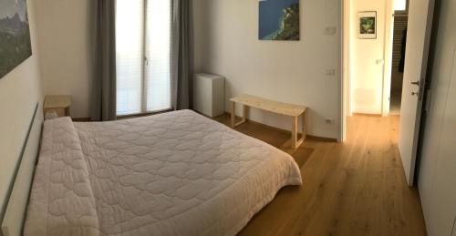 1 dormitorio con cama blanca y suelo de madera en Casa betulla, en Castion Veronese