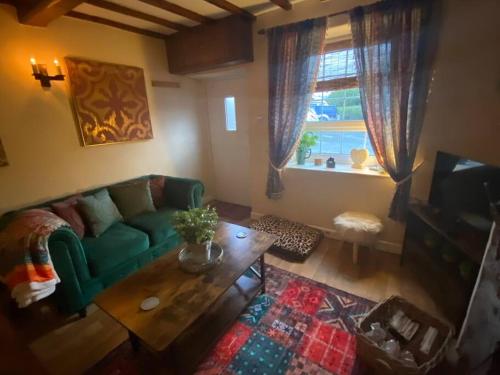 a living room with a green couch and a coffee table at Maytree Cottage. Compact home in Mid Wales. in Llanrhaeadr-ym-Mochnant