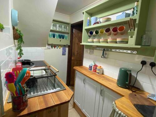 a kitchen with green cabinets and a counter top at Maytree Cottage. Compact home in Mid Wales. in Llanrhaeadr-ym-Mochnant