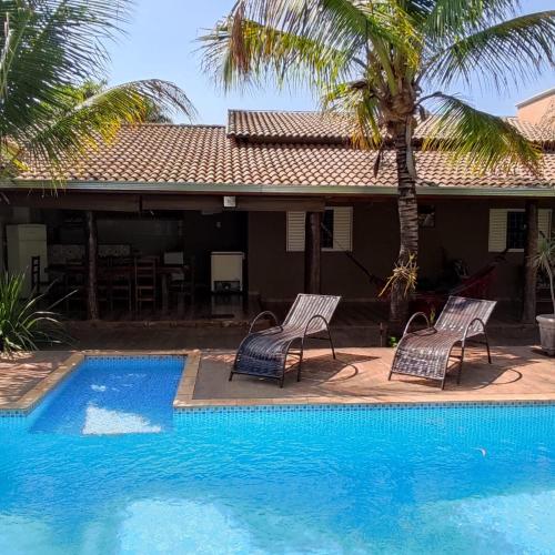duas cadeiras e uma piscina em frente a uma casa em Chácara talismã 3 em Olímpia
