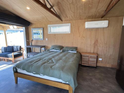 1 dormitorio con 1 cama y 1 sofá en una habitación en The Raglan Harbourside Hutch, en Raglan