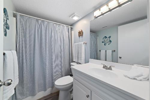 y baño con lavabo, aseo y espejo. en Seacrest 507, en Gulf Shores