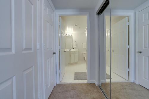 La salle de bains est pourvue de murs blancs et d'une porte en verre. dans l'établissement Quiet Condo in the Heart of Ballston, à Arlington