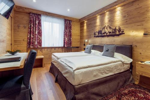 een slaapkamer met een bed en een bureau bij Hotel Columbia & Spa in Cortina dʼAmpezzo