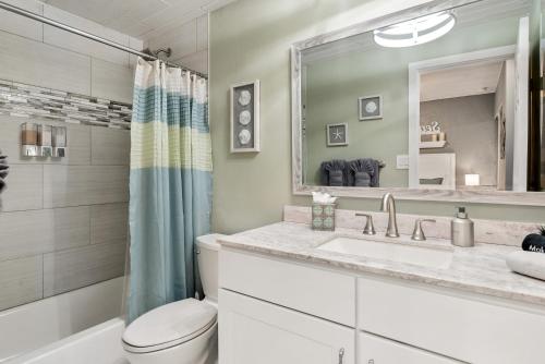 a bathroom with a sink and a toilet and a mirror at Seashells Getaway - Boat Slip, Ramp, Pool in Marathon