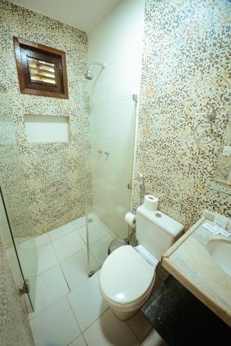 a bathroom with a toilet and a shower and a sink at Hotel Aconchego Porto de Galinhas in Porto De Galinhas