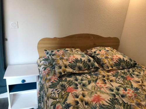 - un lit avec une couette à fleurs et une table de chevet dans l'établissement Studio 22m2 classé * calme et accès direct Plage, à Saint-Hilaire-de-Riez