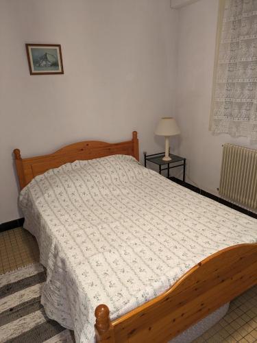 1 dormitorio con cama de madera y edredón blanco en Pin parasol en Marmande