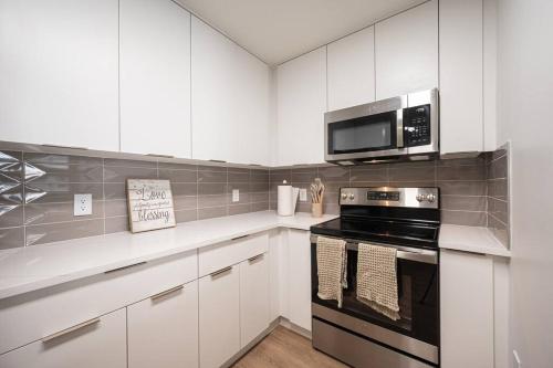 a kitchen with white cabinets and a stove and microwave at Uptown Charlotte Style in Charlotte