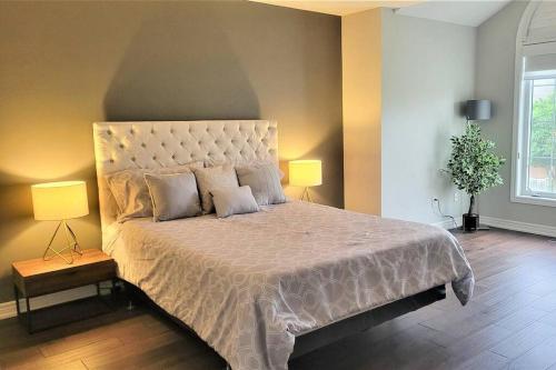 een slaapkamer met een groot bed met 2 lampen bij Centrally Located Stylish House in Vaughan