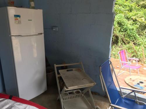 uma cozinha com um frigorífico, uma mesa e cadeiras em Camping Toninhas em Ubatuba