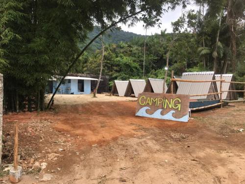 um sinal sentado na terra em frente a um edifício em Camping Toninhas em Ubatuba