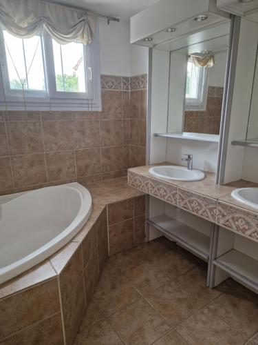La salle de bains est pourvue de 2 lavabos, d'une baignoire et d'un miroir. dans l'établissement Maison familiale à caumont sur durance, à Caumont-sur-Durance