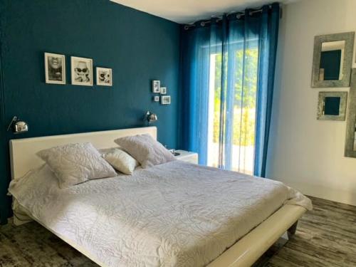 - une chambre avec un lit aux murs bleus et une fenêtre dans l'établissement Maison familiale à caumont sur durance, à Caumont-sur-Durance