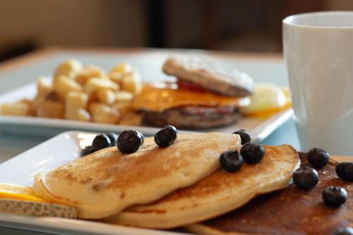 a plate of pancakes with fruit on it with a cup of coffee at Rodd Grand Yarmouth in Yarmouth