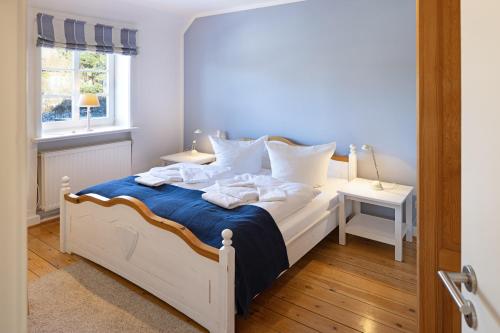ein Schlafzimmer mit einem weißen Bett mit blauer Bettwäsche und Kissen in der Unterkunft Erika in List