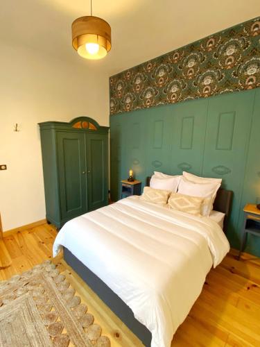 a bedroom with a large white bed with a green wall at Cocon cosy dans la ville rose in Toulouse