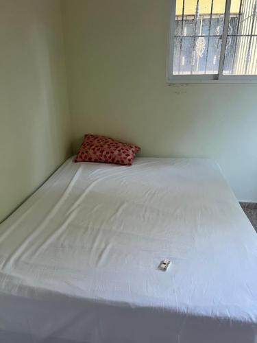 a white bed in a room with a window at Residencial Peralta in Pedernales