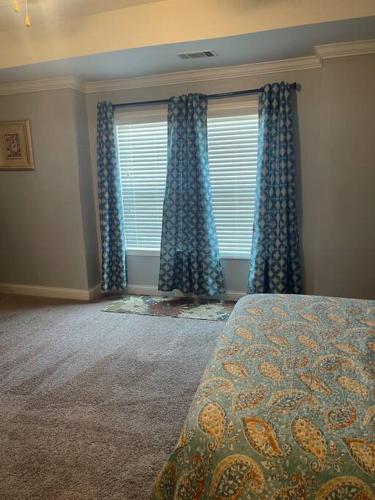 a bedroom with a bed and a window with blue curtains at Spacious Home Near Shaw in Sumter