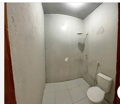 a bathroom with a white toilet and a white tile floor at Seu lar Fora de Casa! in Juazeiro do Norte