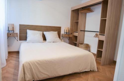 une chambre avec un lit blanc avec une tête de lit en bois dans l'établissement 50 m plage & tram superbe appart récent, à Nice