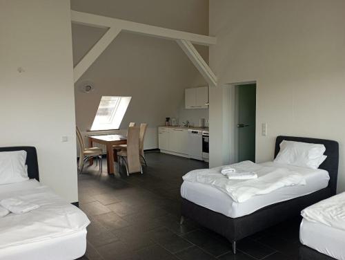 Duas camas num quarto com uma cozinha e uma mesa em Ferienwohnungen Fabry 2 2 em Saarbrücken