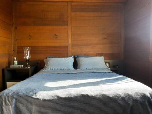 ein Schlafzimmer mit einem Bett mit einer Holzwand in der Unterkunft Linda Casa Sonnenhaus Witmarsum in São Luís do Purunã