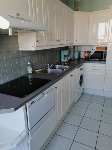 une cuisine avec des armoires blanches, un évier et un lave-vaisselle dans l'établissement Les Terrasses de Marcq, à Marcq-en-Barœul