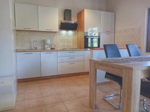 a kitchen with white cabinets and a table with blue chairs at Apartments Franić in Saplunara