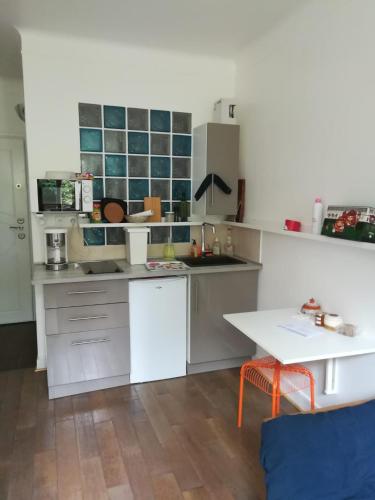 une cuisine avec des armoires blanches et une table dans l'établissement studio rdc bois de vincennes, à Saint-Mandé