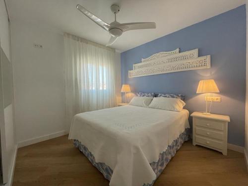 1 dormitorio con cama blanca y pared azul en Apartamento Centro Nerja proxi playas, en Nerja