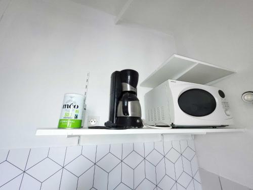 un four micro-ondes et une cafetière sur une étagère dans la cuisine. dans l'établissement Studio 2 - Rouen Centre Ville, à Rouen