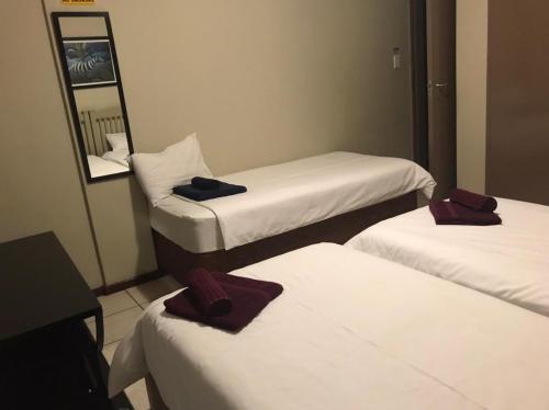 een hotelkamer met 3 bedden en een spiegel bij Libem Lodge 11 in Edenvale