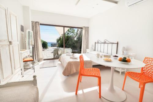 Habitación blanca con cama, mesa y sillas en Louiza Apartments, en Agios Gordios