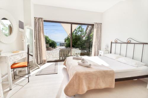 a white bedroom with a bed and a large window at Louiza Apartments in Agios Gordios