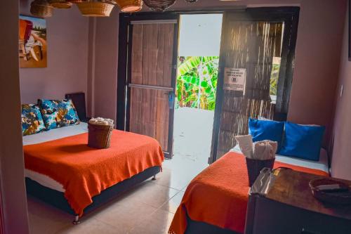 a bedroom with two beds with orange sheets and a door at Hotel Shaddai in Villavieja