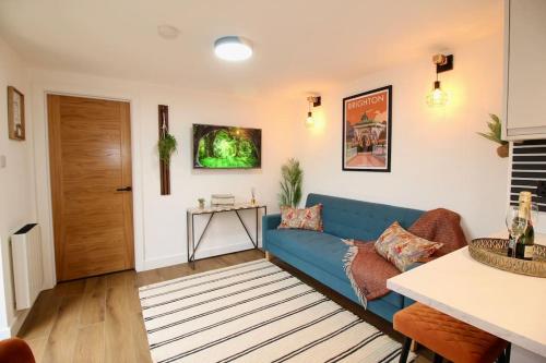 a living room with a blue couch and a table at The Coastal Retreat (Nr Brighton) in Peacehaven