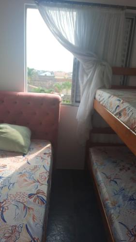 a bedroom with two bunk beds and a window at Apartamento em Itanhaém com 2 quartos, Piscina e Ampla Varanda Gourmet in Itanhaém