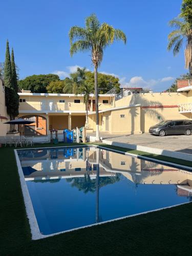 einen Pool vor einem Haus mit einer Palme in der Unterkunft Hotel 20 De Julio in Cuernavaca