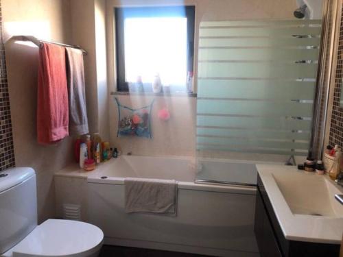 a bathroom with a tub and a toilet and a sink at MAISON DE FAMILLE À 20 MN DE LISBONNE ET SETÚBAL in Quinta do Conde