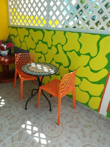 uma mesa e duas cadeiras ao lado de uma parede em appartement les hibiscus em Grand-Bourg