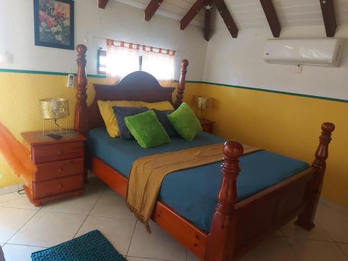 um quarto com uma cama de madeira e almofadas verdes em appartement les hibiscus em Grand-Bourg