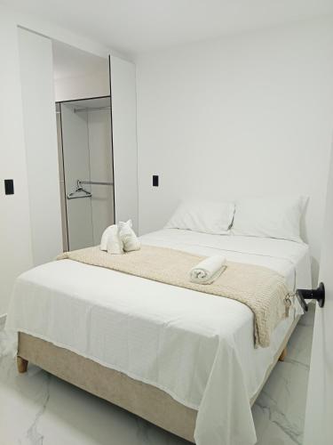 a white bedroom with a large bed and a mirror at perla del norte in Bello